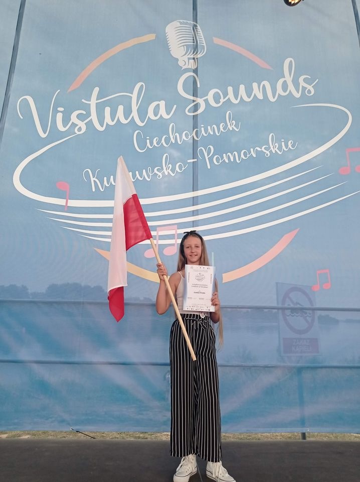 Na zdjęciu Oliwia Pitura z flagą Polski i dyplomem .