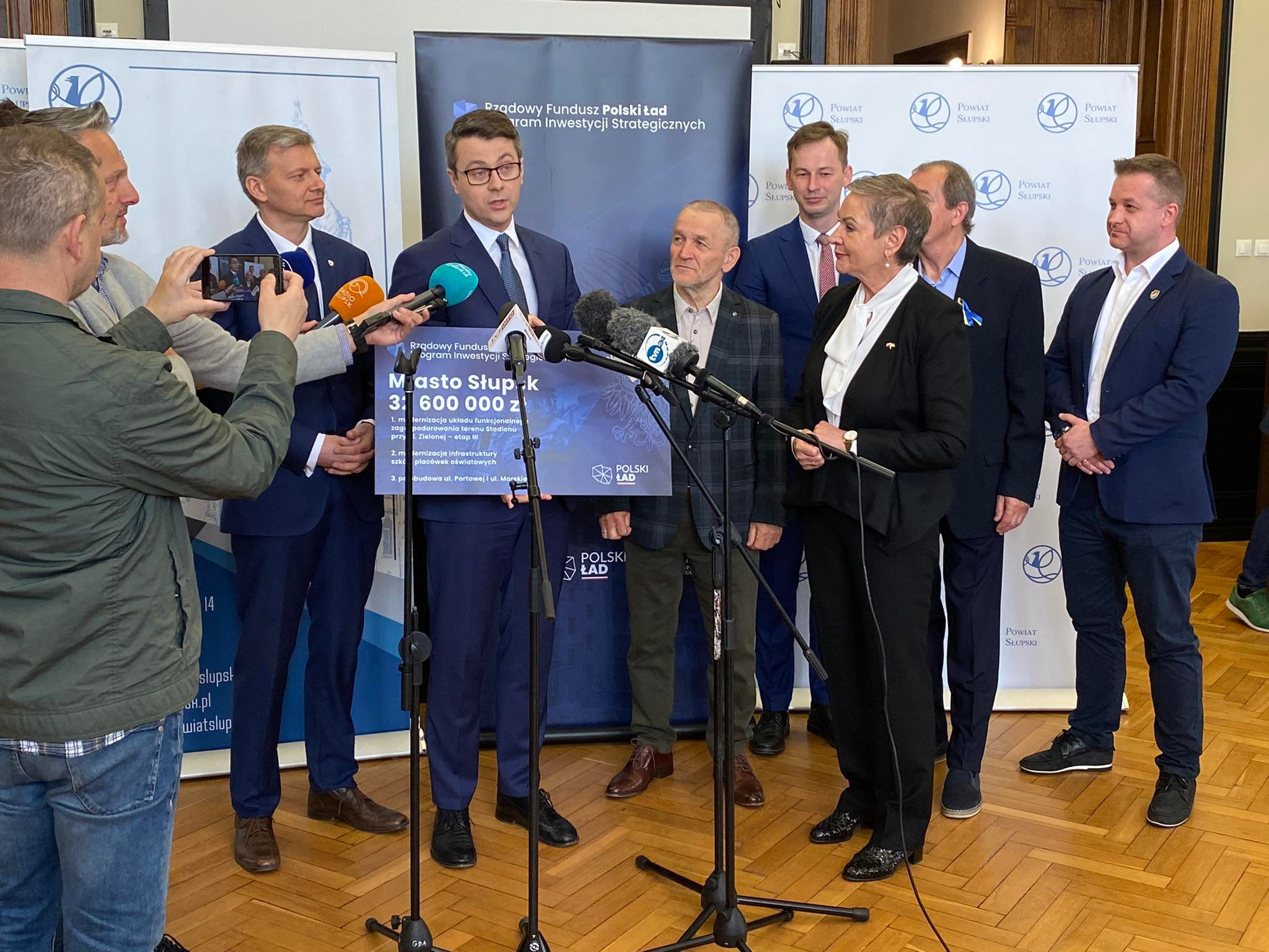 Na zdjęciu widzimy Prezydentkę Miasta, Posła na Sejm RP trzymającego tablicę z dofinansowaniem jak w treści artykułu, radnych PiSu oraz mikrofony dzienniakrskie
