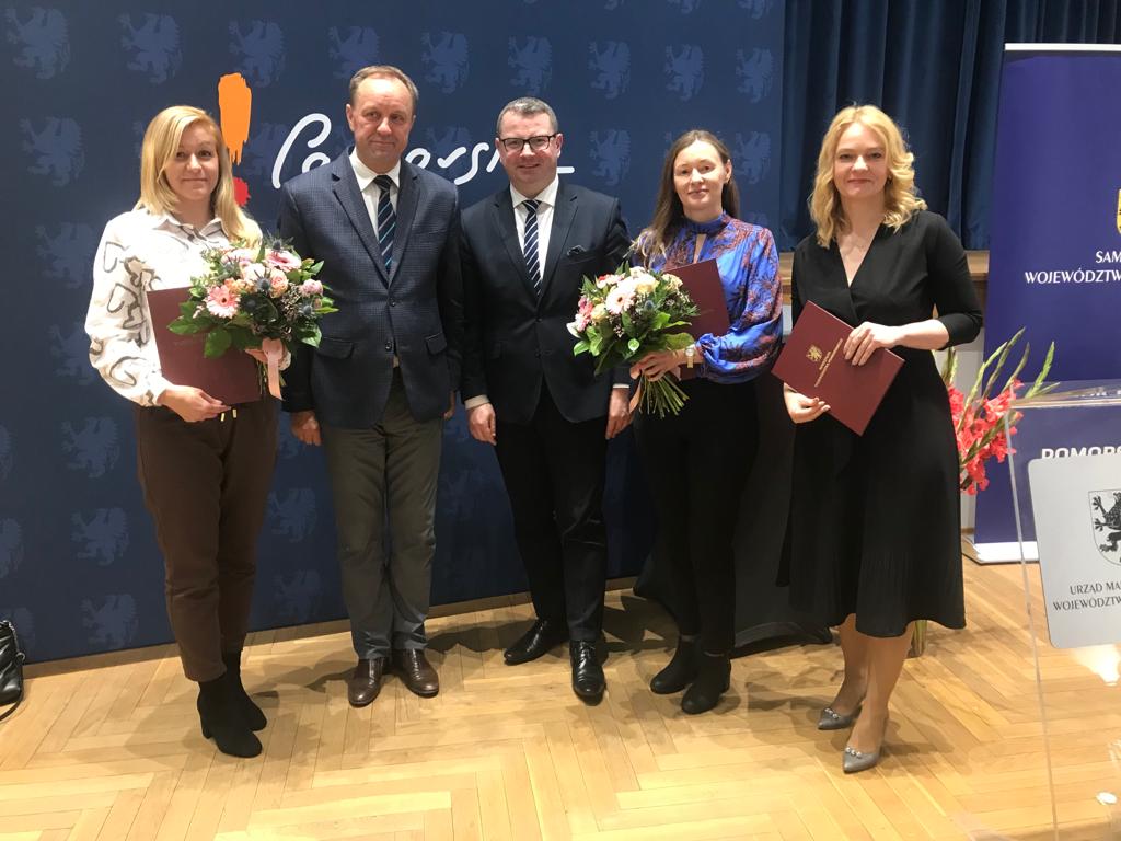 Na zdjęciu widzimy 5 osób - 3 Finalistki oraz Marszałek Woj.Pomorskiego wraz z Wiceprezydentem Słupska, dwie z Pań trzymają oprócz teczek - bukiety kwiatów, jedna z kobiet trzyma tylko teczkę