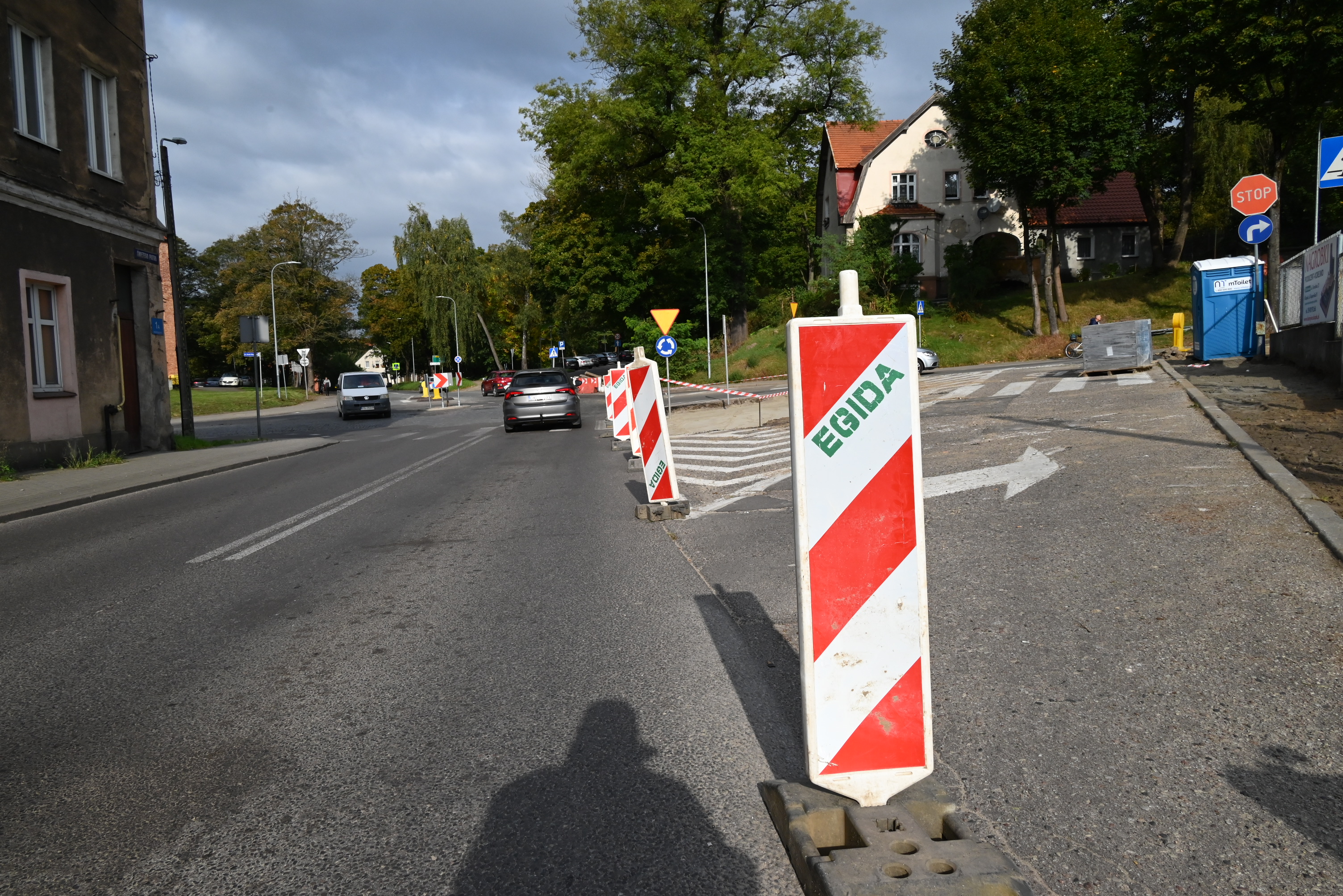 Ulica ze znacznikami wskazującymi na prowadzone prace przygotowawcze, widok na rondo i auta