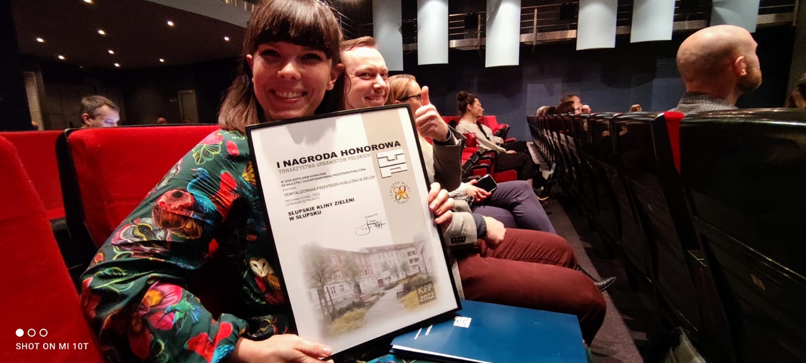 autorka projektu Słupskich Klinów Zieleni - Zuzanna Chudzińska prezentuje nagrodę dla Słupska, w tle inni uczestnicy gali