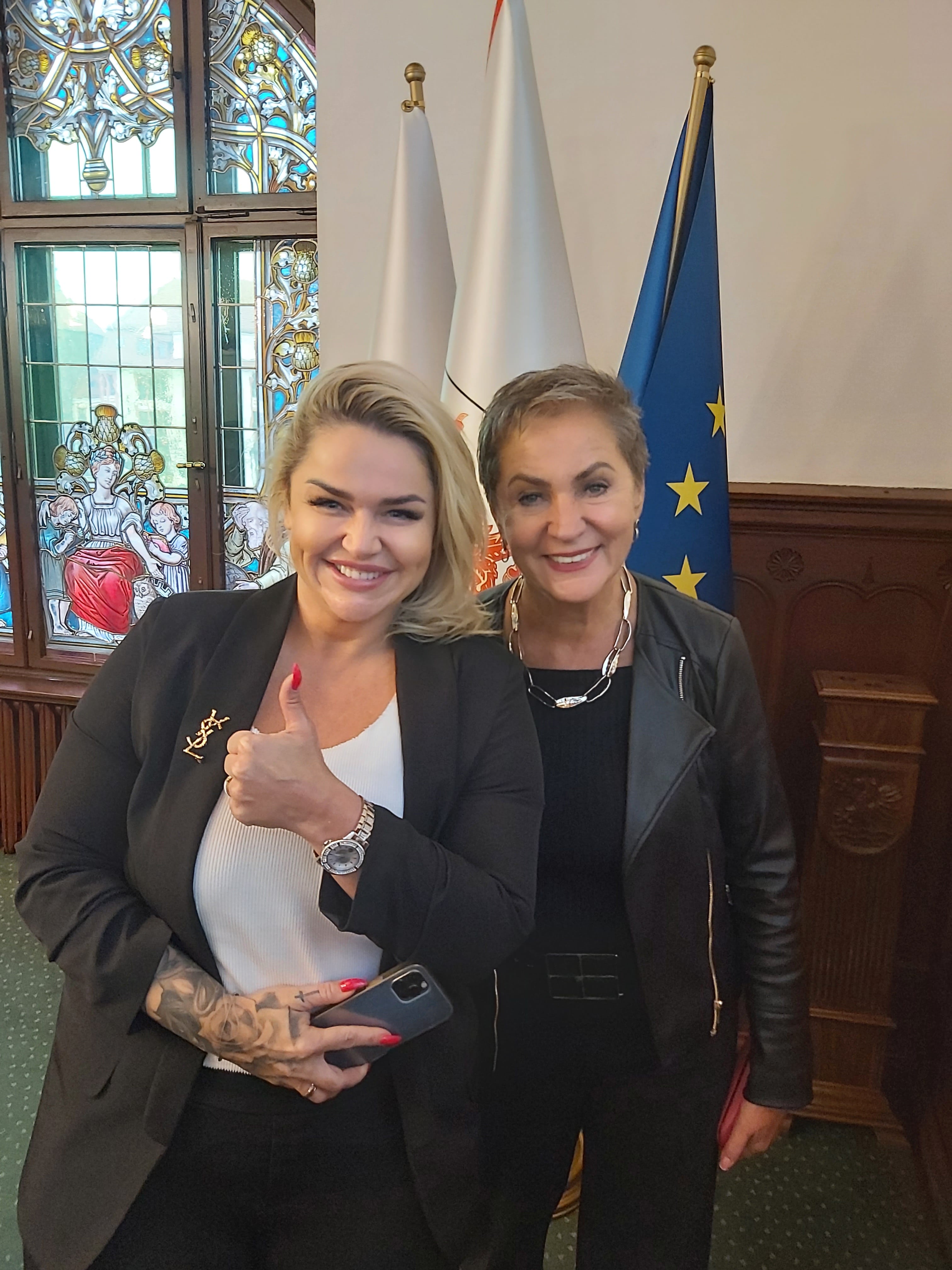 Prezydentka Słupska z jedną ze Sponsorek Gali ; w tle flaga UE, Polski i witraże
