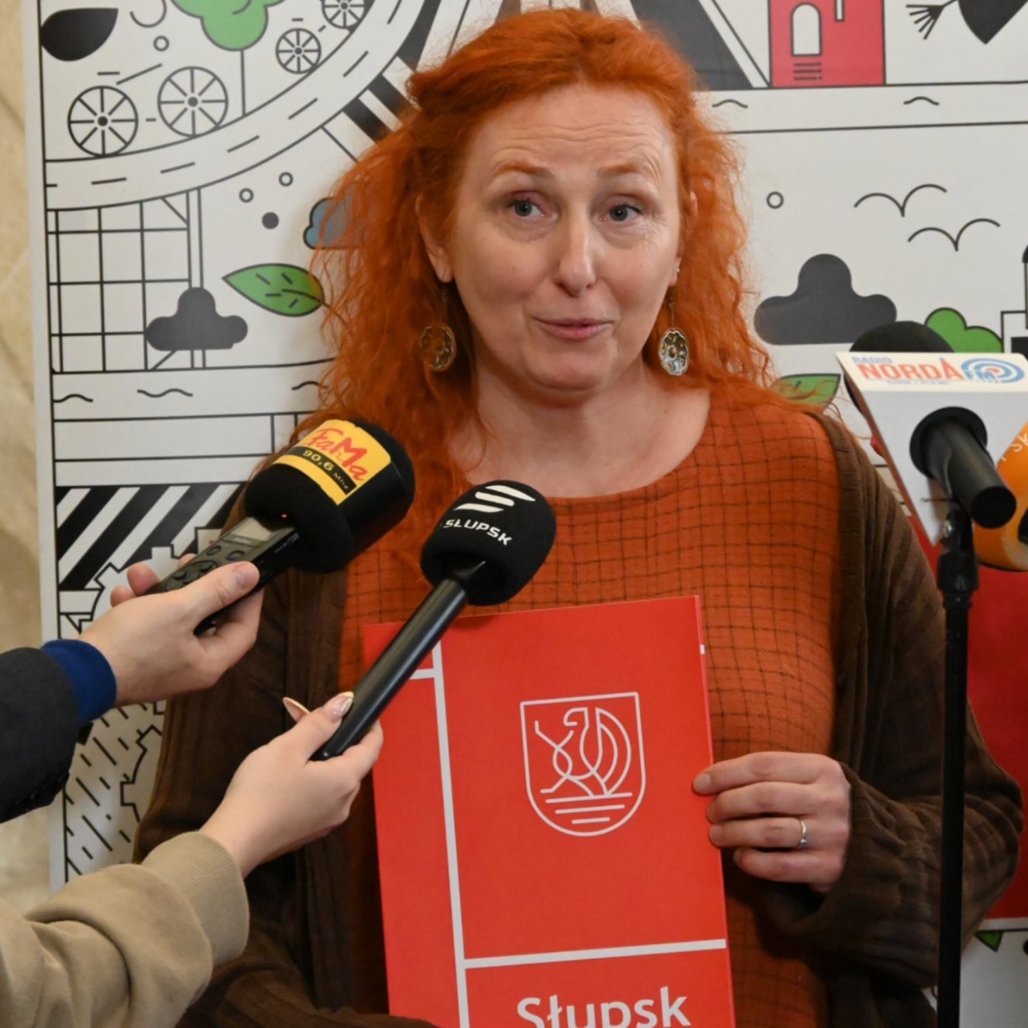 Kobieta w długich włosach trzymam w dłoniach czerwony dyplom