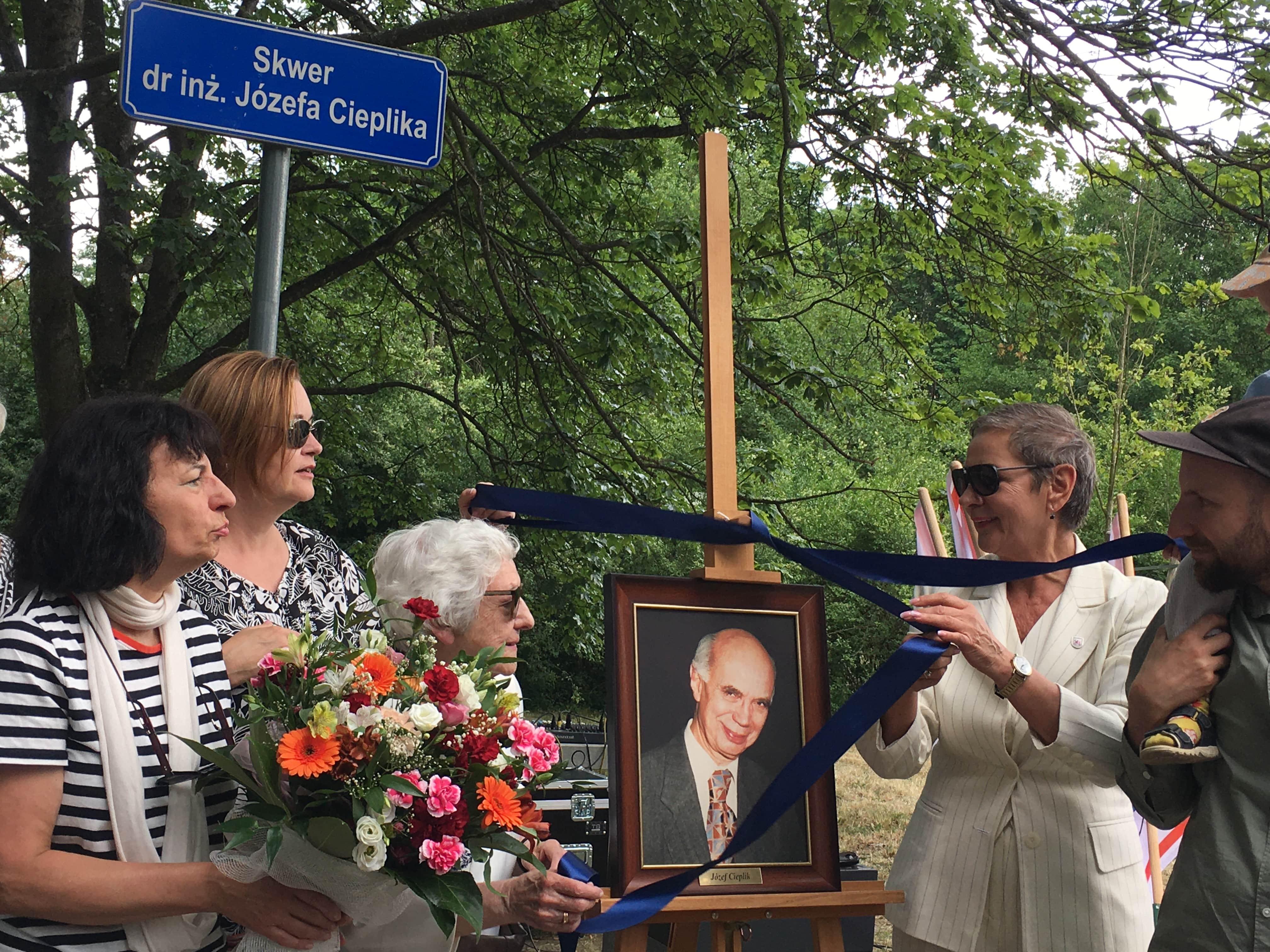 Prezydentka, Pani Janina oraz Przewodnicząca ściągają wstążkę z obrazu Patrona symbolicznie otwierając Skwer Józefa Cieplika