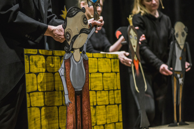 aktorzy trzymają w dłoniach postacie  z kartonu w stylu komiksowym- lalki ze spektaklu :"Śniezka"