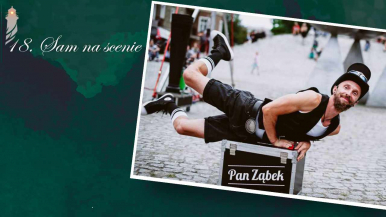 mężczyzna z brodą i czarnym meloniku w pozycji leżącej ze zgiętymi nogami na srebrnej skrzyni z napisem Pan Ząbek