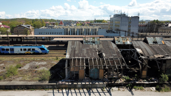Zdjęcie przedstawia widok na zriunowany były budynek kolejowy, perony oraz dworzec kolejowy