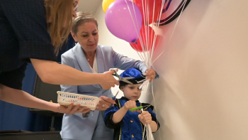 Prezydentka Miasta Słupska Krystyna Danilecka-Wojewódzka wraz z chłopcem przecinają balony i odsłaniają tablicę z logo przedszkola.