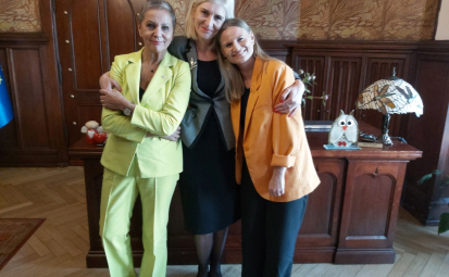 Beata Pawlicka z Prezydentkami Krystyną Danilecką-Wojewódzką i Martą Makuch, w tle biurko m.in. z bukietem kwiatów