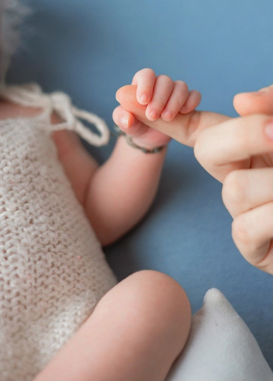 Na zdjęciu niemowlę trzyma swoją ręką palec dorosłej osoby