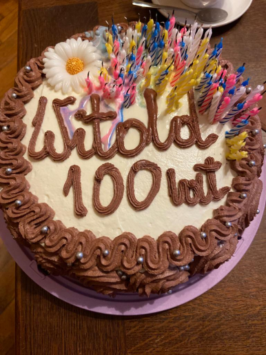 Na zdjęciu widzimy tort z napisem WITOLD 100 LAT z ozdobnym kwiatkiem i świeczkami.
