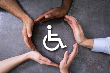 na zdjęciu widzimy symbol osoby niepełnosprawnej na wózku inwalidzkim, otoczony dłońmi
