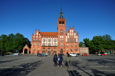 Zdjęcie Ratusza, kobiety na Placu Zwycięstwa idące w kieunku Ratusza