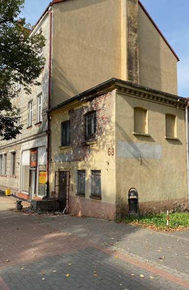 Zdjęcie przedstawia nieruchomość zabudowaną budynkiem dwukondygnacyjnym przeznaczoną na sprzedaż