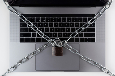 Na zdjęciu pokazana jest klawiatura laptopa przewiązana łańcuchami po przekątnych i spiętymi kłódką na środku