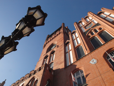 budynek ratusza widziany od dołu, po lewej stronie lampa uliczna, błękitne niebo w tle