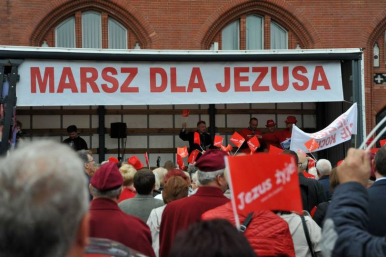 Osoby zgromadzone przed mini sceną z napisem MARSZ DLA JEZUSA