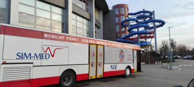 Zdjęcie przedstawia autobus (Mobilny Punkt Poboru Wymazów) stojący pod Parkiem Wodnym "Trzy Fale"