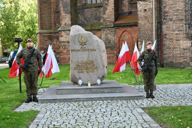 Dwaj Żołnierze Wojska Polskiego trzymają wartę podczas uroczystości; na środku Pomnik Polskiego Państwa Podziemnego ; w tle Kościół Mariacki