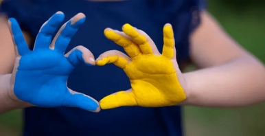 Na zdjęciu widzimy pomalowane dłonie dziecka. Jedna dłoń jest pomalowana na niebiesko druga na żółto.