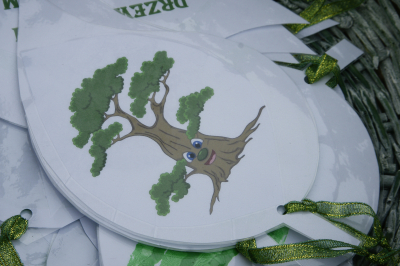 zdjęcie przedstawiające rysunek drzewa na wyciętej kartce przewiązanej na dole zieloną wstążką - forma zawieszki