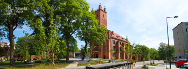 Budynek Biblioteki z czerwonej cegły w otoczeniu zielonych drzew