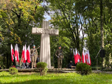 Krzyż Katyński na Starym Cmentarzu , żołnierze asystujący podczas uroczystości i flagi Rzeczypospolitej Polskiej