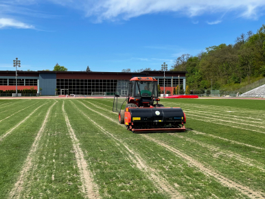 Traktor pracuje na zielonej płycie stadionu 650-lecia w Slupsku.