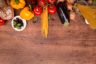 zdjęcie jedzenia - makaron, papryka, pomidory, bakłażan, cebule, chleb leżące na drewnianym stole