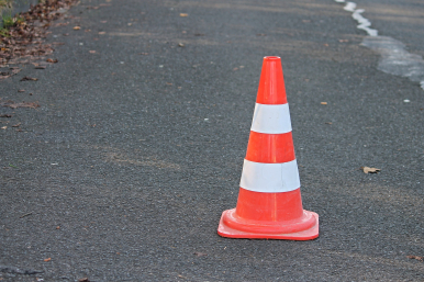 jezdnia asfaltowa a na niej stojący pomarańczowo-biały pachołek ostrzegawczy; Image by Manfred Richter from Pixabay