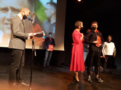 Na zdjęciu widzimy sześć osób na scenie Teatru RONDO -Panią Prezydent w czerwonej sukience na pierwszym planie oraz nagradzonego sportowca jak również Pełnomocnika Prezydenta ds. Sportu