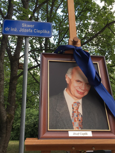 Zdjęcie pokazuje obraz - namalowany portret Pana Józefa Cieplika, ustawiony na sztaludze. W tle park i tabliczka z napisem "Skwer dr inż.Józefa Cieplika"