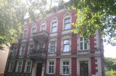 Zdjęcie przedstawia budynek, w którym znajduje się lokal mieszkalny na sprzedaż.