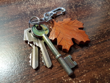 Na zdjęciu widzimy pęk kluczy do drzwi z drewnianym brylokiem w kształcie liścia