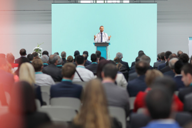 Na zdjęciu widzimy siedzących ludzi i pana prowadzącego konferencję