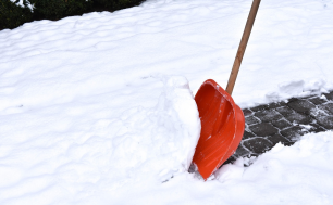 Zdjęcie przedstawia nagromadzony świeży śnieg zalegający na chodniku i odśnieżany łopatą
