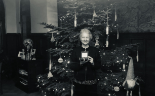 Czarno-białe zdjęcie Pani Mirosławy Bajerskiej na tle choinki bożonarodzeniowej