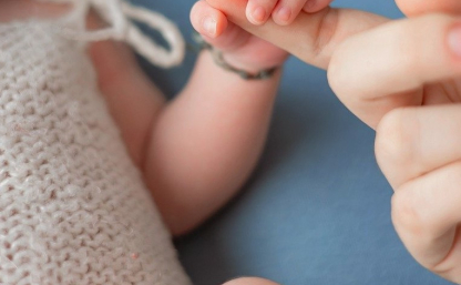 Na zdjęciu niemowlę trzyma swoją ręką palec dorosłej osoby