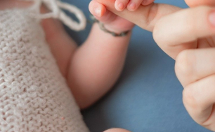 Na zdjęciu niemowlę trzyma swoją ręką palec dorosłej osoby