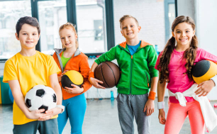 na zdjęciu czworo dzieci - dwoje chłopców i dwie dziewczynki. Dzieci ubrane na sportowo, w rękach trzymają piłki