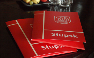 dwie czerwone teczki z napisem Słupsk i logo miasta leża na stoliku