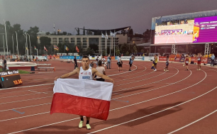 Marek Zakrzewski z biało-czerwoną flagą na bieżni stadionu.