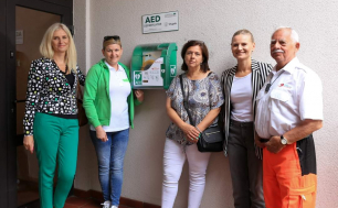 Na zdjęciu widizmy 5 osób, w tym m.in. Wiceprezydentkę Makuch; na zdjęciu są 4 kobiety i 1 mężczyzna, stoją przy ścianie, przy której zamontowany jest defibrylator AED. Fot. Biblioteka Słupska