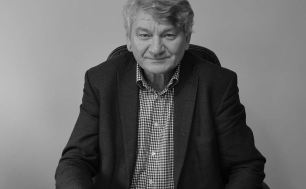 Fotografia Wójta Kulińskiego przy biurku; na blacie dokumenty, okulary; źródło: Obserwator Słupsk