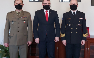 Na zdjęciu widzimy trzech mężczyzn - dwóch w mudnurach wojskowych. Zdjęcie zrobione w gabinecie Wiceprezydenta Miasta Słupska, w tle widać obrazy/zdjęcia w ramach. Panowie mają założone maseczki ochronne, jeden z nich ma okulary