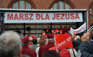 Osoby zgromadzone przed mini sceną z napisem MARSZ DLA JEZUSA