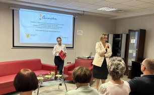 Na zdjęciu stoi Zastępca Prezydenta Miasta Słupska Pani Beata Chrzanowska w czasie prelekcji z mikrofonem w dłoni, na drugim planie stoi Pani Hanna Rugała z Uniwersytetu Pomorskiego trzymając czerwoną teczkę w dłoni, obie stoją w sali SCOPIES podczas Kampanii informacyjnej o demencji