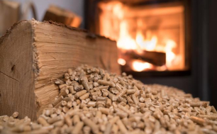 zdjęcie przedstawia ogień tlący się w kominku, rozsypany pellet drzewny oraz kawałek drewna (fot. pixabay)
