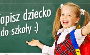 Na tle tablicy dziewczynka z podniesionym kciukiem do góry