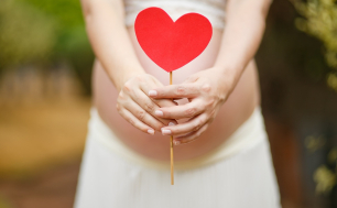 Zdjęcie przedstawia kobietę w ciąży trzymającą serduszko na patyku - symbol miłości i troski, źródło pixabay.com